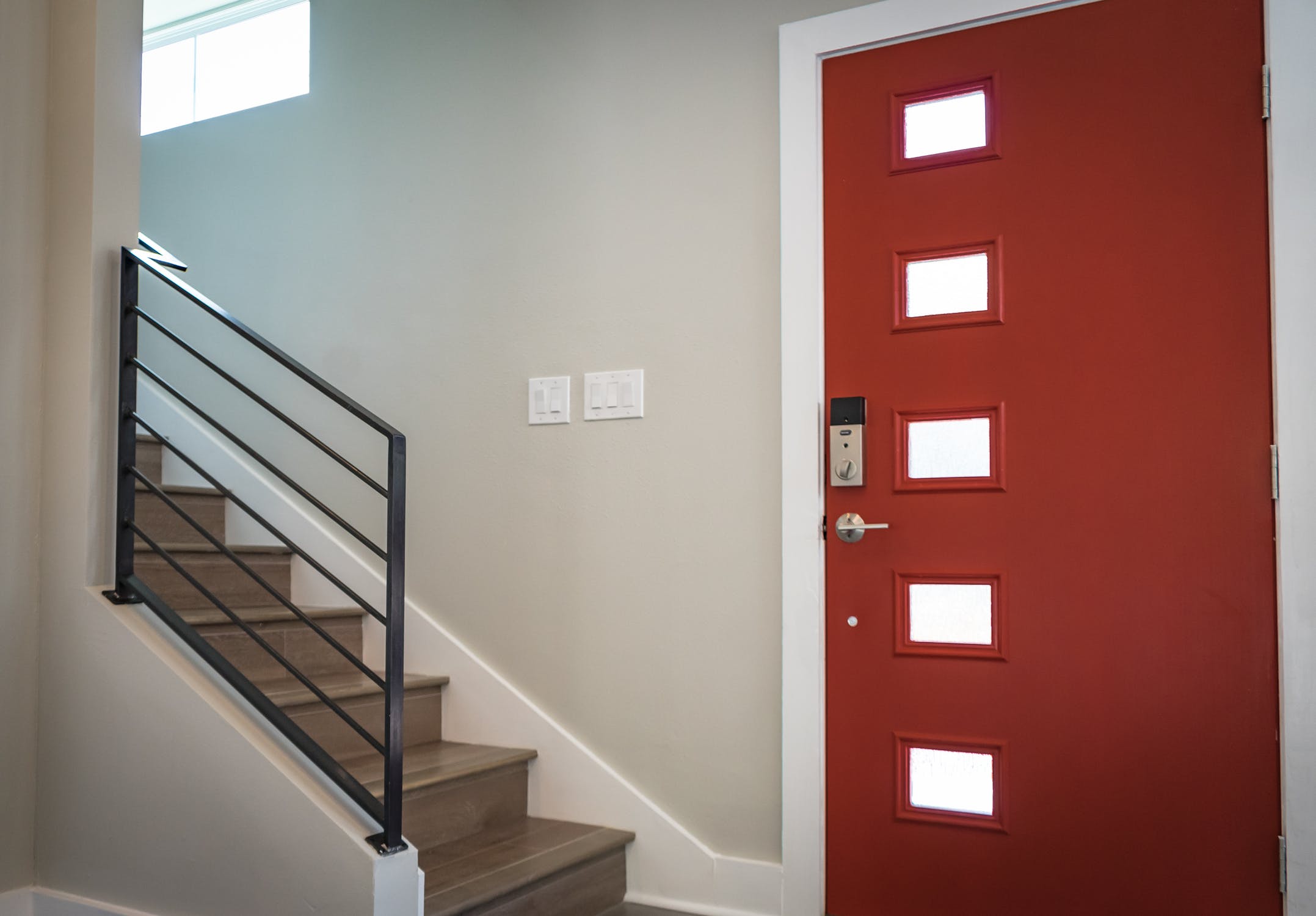 Hall d'entrée moderne avec porte rouge et escaliers contemporains